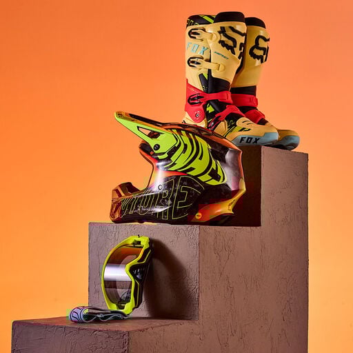 Brightly colored mx boots, helmet, and goggles on stone stairs