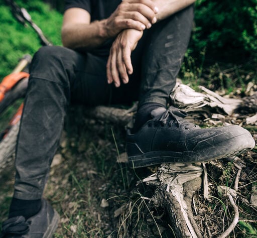 Man sitting on the side of a mountain bike trail.